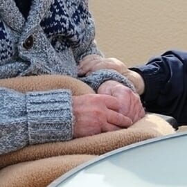 elderly person holding their hands in nursing home