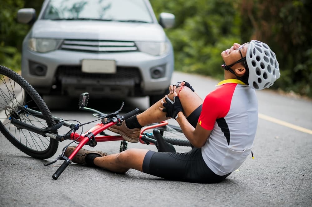 Mountain biker injured in car collision on road, emphasizing need for road safety. Selective focus.