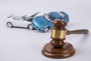 Two collided cars on a white background, symbolizing an accident. Issues of insurance and court cases may arise, involving the hammer of the judge.